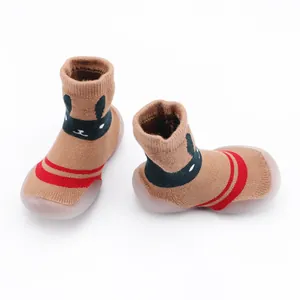 Detail view of brown knit baby sock shoes with cute bunny face and red stripes