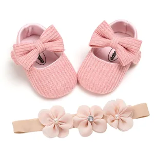 Close-up detail of soft pink knitted baby shoes with matching floral headband set