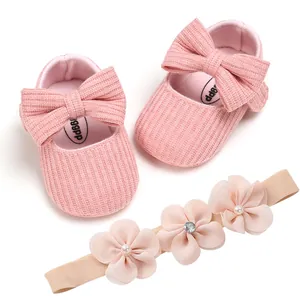 Detail showing pink knitted baby shoes with large bows and matching floral headband