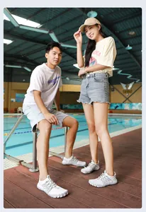 Pareja de adultos con zapatillas de agua blancas de secado rápido en una piscina