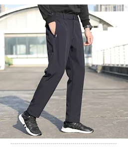 Side view profile of men's sleek black athletic trousers in a modern outdoor setting