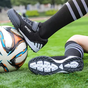 Children's breathable mesh turf soccer shoes with Velcro straps on grass field