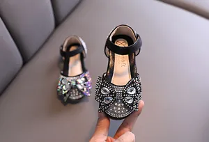 Elegant close-up view of black girl's princess shoes featuring a sparkly rhinestone bow.