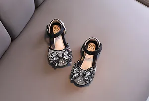 Detailed view of black girl's princess shoes with sparkly rhinestones and bow design