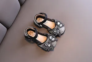 Macro detail view of girls black rhinestone princess dance shoes with sparkling bow accent