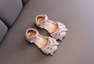 Detailed view of pink princess shoes with sparkling rhinestone bows and pearls.