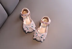 Detailed view of sparkly pink girl's princess shoes featuring a large rhinestone bow