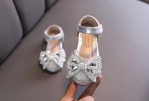 Close-up detail of the sparkling silver rhinestone bow on a girl's princess dance shoe