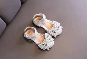Close-up of sparkling silver princess shoes with rhinestone bow and pearl trim detail