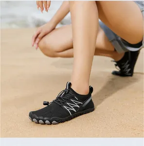 Detalle de zapatos de agua negros transpirables usados en una playa de arena fina