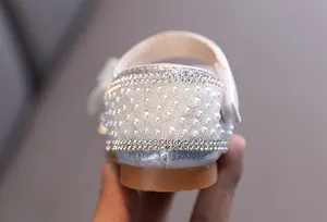 Close-up of sparkling rhinestone and pearl heel on silver girls' princess shoes