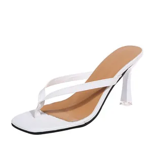 Detail van witte teenslippers met hoge hak en vierkante neus voor een moderne look.