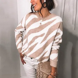 Close-up detail of beige zebra pattern knitted sweater on model with stylish fringed bag