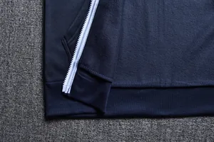 Close-up of navy blue zip-up hoodie showing ribbed hem and white zipper detail