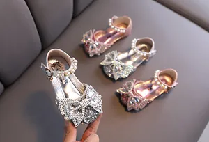 Primer plano de zapatos de princesa para niñas con tiras de perlas y lazos brillantes