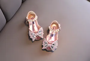 Vista detallada de zapatos de princesa rosas para niña con lazos brillantes y perlas