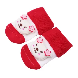 Gros plan de chaussettes bébé rouges et blanches avec une poupée animal en peluche