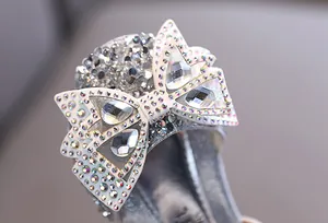 Primer plano de lazo con pedrería brillante en zapatos plateados de baile de princesa