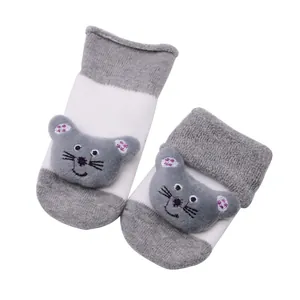 Gros plan de chaussettes de sol pour bébé avec poupée souris et tissu éponge épais.