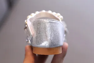 Primer plano del talón de zapato de princesa plateado para niña con perlas blancas.