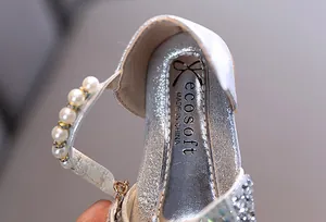 Primer plano de zapato de princesa plateado con brillo y correa de perlas finas