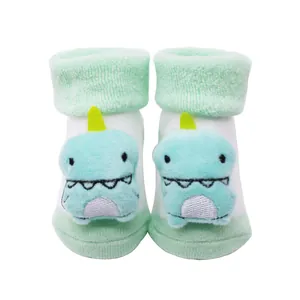 Vue détaillée de chaussettes épaisses pour bébé avec une poupée dinosaure en peluche 3D.