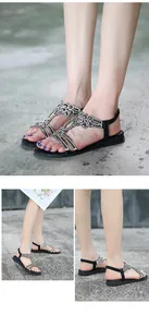 Detail view of black flat sandals with floral rhinestone embellishments on feet