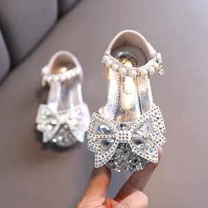 Zapatos de princesa plateados para niñas con lazo de pedrería y detalle de perlas.