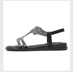 Detailed side profile of black women's flat sandals featuring rhinestone flower strap