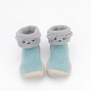 Macro view of cozy blue coral fleece baby sock shoes with cute embroidered cartoon faces