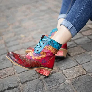 Vue détaillée de bottines vintage élégantes à motif floral et lacets sur une rue pavée.