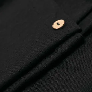Primer plano de la textura de tela de punto negra con un pequeño botón de madera