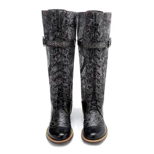 Vista frontal detallada de botas con cordones y complejos motivos florales en relieve