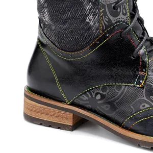 Primer plano de botas de cuero negro con costuras coloridas y un patrón floral