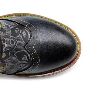 Detalle de la puntera de bota negra con costuras arcoíris y diseño en relieve