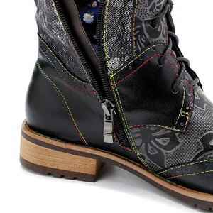 Primer plano de bota motera negra con costuras coloridas y cremallera lateral de metal