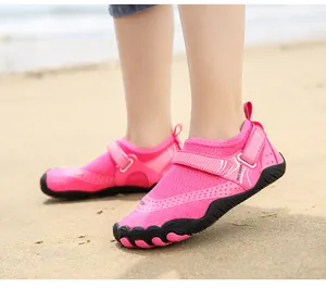 Detailed view of pink kids quick-dry water shoes worn on a sandy beach for outdoor swimming