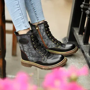 Gros plan sur des bottines motardes gothiques noires avec coutures colorées et toile florale.