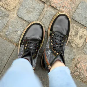 Détail de bottines plates gothiques rétro à lacets avec des surpiqûres colorées uniques.