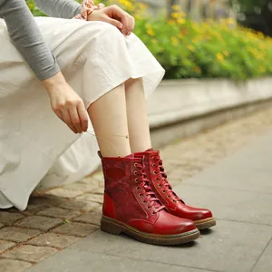 Gros plan de bottines gothiques rouges à lacets de style vintage portées avec une jupe.