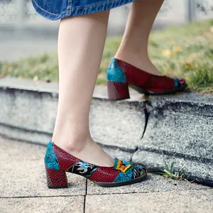Primer plano de zapatos de tacón patchwork de colores con mariposa decorativa en escalones