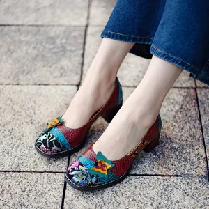 Detalle de zapatos patchwork de cuero colorido con un vibrante adorno de mariposa 3D