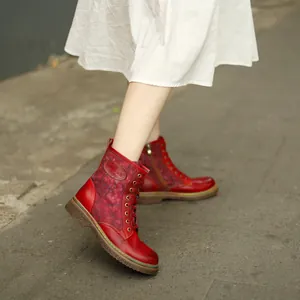 Détail de bottines rouges rétro à lacets style moto portées avec une robe blanche