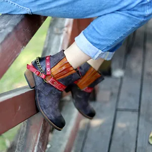 Vue détaillée de bottines en daim faites à la main avec des brides en cuir rouge
