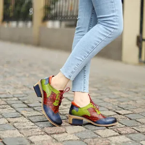 Detail of retro ethnic patchwork brogue shoes with colorful leather on stone street.