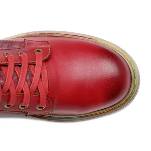 Gros plan de la botte gothique en cuir rouge avec coutures colorées et lacets rouges.