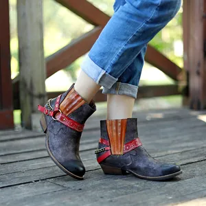 Vue détaillée de bottines de cowboy usées avec bride rouge et détails de chaînes