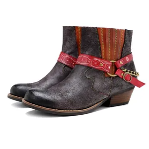Détail de bottines western artisanales dépolies avec lanières ethniques et chaîne métal