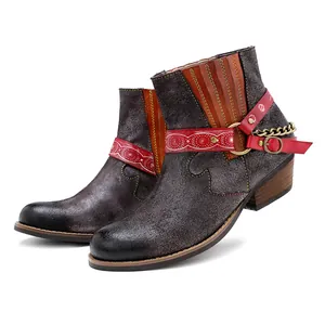 Gros plan de bottines de cowboy en daim avec lanières rouges et détails de chaîne