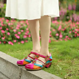 Close-up of vintage colorful flower wedge Mary Jane sandals on feet in a garden.